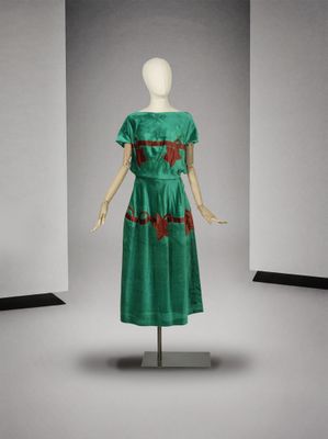 une photo d'un mannequin portant une robe verte ornée de fleurs rouges