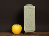 a green vase and an apple sitting on a table