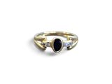 un gros plan d'une bague en or sertie d'une pierre noire et de diamants