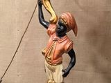 une statue représentant un homme tenant un candélabre posé sur une table