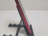 a red cell phone sitting on a stand on a white table
