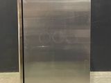 stainless steel refrigerator in a warehouse with a black wall in the background