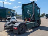 a green semi truck parked in a lot with other semi trucks