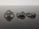 trois bagues en diamant posées sur une surface noire, sur fond blanc