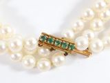 two strands of white pearls with emeralds and a gold clasp