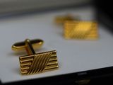 two gold cufflinks in a box on a table