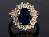 a close up of a ring with a blue stone surrounded by white diamonds