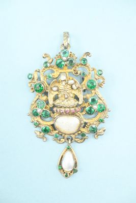 a close up of a gold pendant with green and white stones