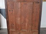 an old wooden cabinet with a wooden door and a painting on the wall behind it
