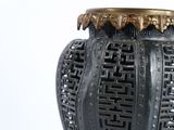 a black vase with a gold lid sitting on a table