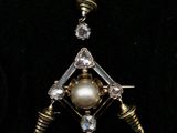 un gros plan sur un collier orné d'une perle et d'un diamant
