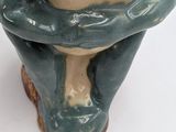 a ceramic figurine of a man sitting on top of a toilet