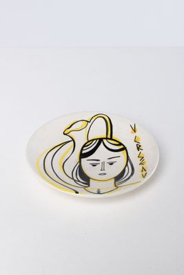 a white plate with a drawing of a woman ' s face on it