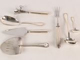 a lot of silverware on a white table