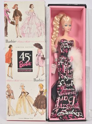 une poupée dans une boîte rose, vêtue d'une robe noire et blanche et d'une étole en fourrure
