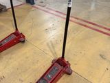two red jacks sitting on the floor in a garage