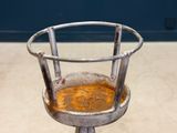 a metal chair with a rusted seat sitting on the floor