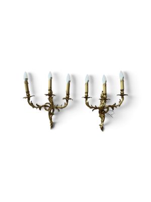 a pair of brass sconces mounted on a wall
