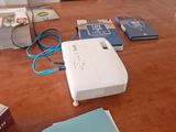 a table with a projector, books, and other items on it