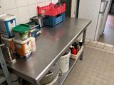 a kitchen with a stainless steel table and a metal shelf with pots and pans on it