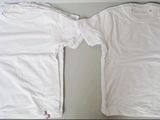 two white t - shirts sitting on top of a table next to each other