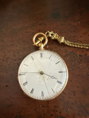 une montre de poche posée sur une table, avec une chaîne autour