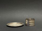 an old silver cup and saucer sitting on a black surface