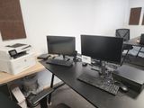 a desk with two computer monitors and a printer on it