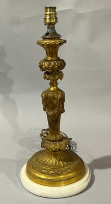 une lampe en or posée sur un socle en marbre