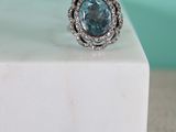 a close up of a ring with a blue topaz stone surrounded by white diamonds