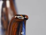 a close up of a glass vase with a blue handle