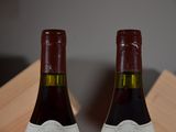 two bottles of wine sitting on top of a table next to each other