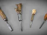 quatre types différents d'outils de sculpture sur bois posés sur une surface grise