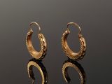 a pair of gold hoop earrings on a reflective surface