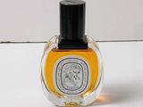 une image représentant un flacon de parfum posé sur une surface blanche