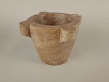 a stone vase with a handle on a white surface