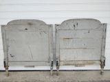 two metal beds sitting next to each other in front of a garage door