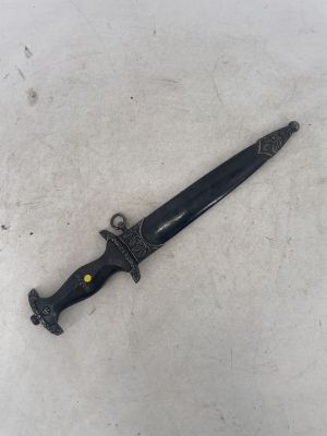 a close up of a knife on a white surface with a black handle
