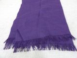 a purple scarf with fringes laying on a bed