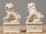 pair of white porcelain foo foos on pedestals on wooden table