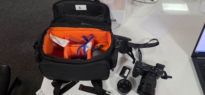 un sac noir contenant des objets orange, posé sur un bureau