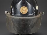 an old fireman ' s helmet on a stand against a black background
