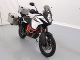une moto blanche et orange garée dans une pièce blanche