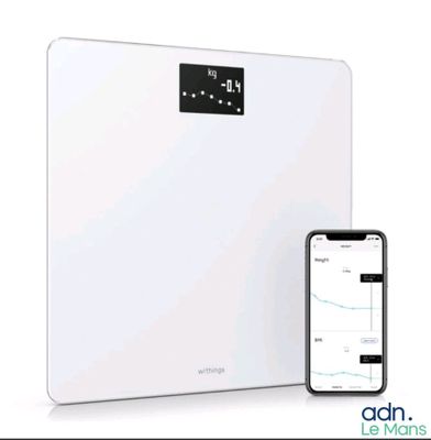 un gros plan d'une balance connectée avec un téléphone portable à côté