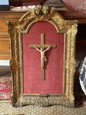 une photo d'un crucifix dans un cadre doré, posée par terre
