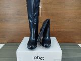 une paire de bottes noires à talons hauts posée sur une boîte blanche