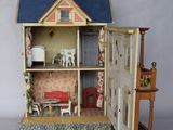 une maison de poupées dont la porte est ouverte, laissant entrevoir un salon