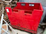 une boîte rouge posée par terre à côté d'un tas de bois