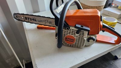 an orange and black chainsaw sitting on top of a white table