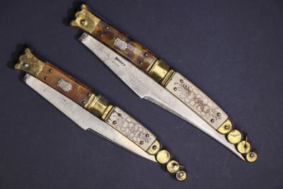 deux couteaux aux manches dorés sur une surface noire